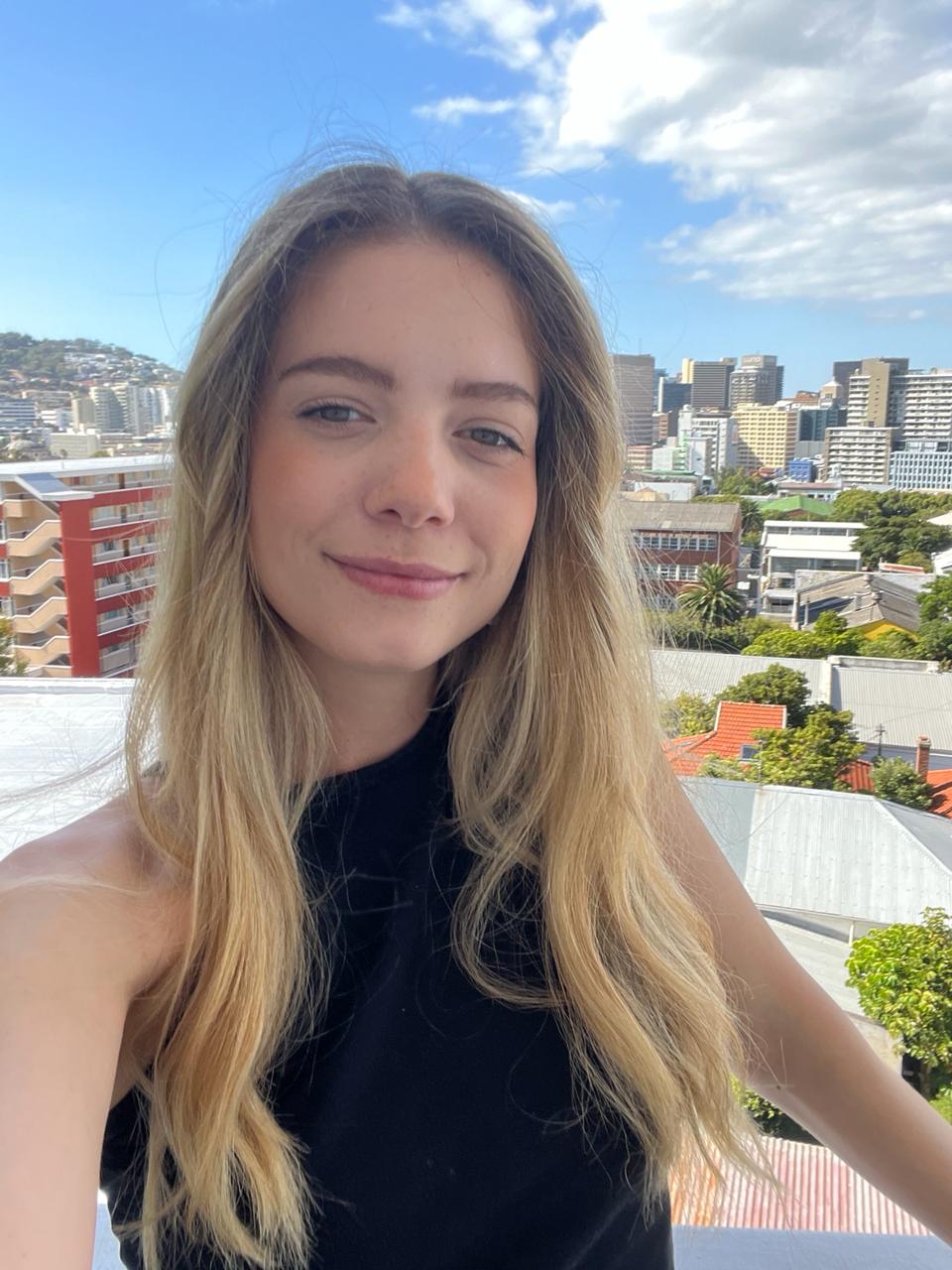 Portrait of a man with brown hair and glasses on a flat gray background.